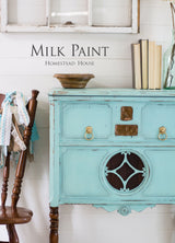 Dresser painted with Laurentien Milk Paint by Homestead House next to a wooden chair and books.
