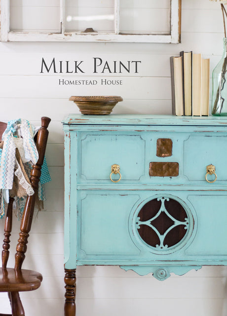 Dresser painted with Laurentien Milk Paint by Homestead House next to a wooden chair and books.