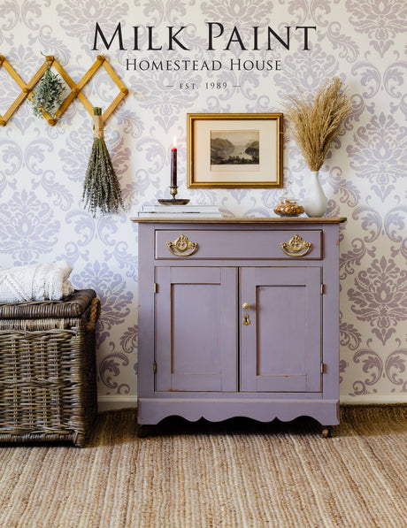 Cabinet painted in Homestead House Lavande Milk Paint, styled with decor and a wicker basket.