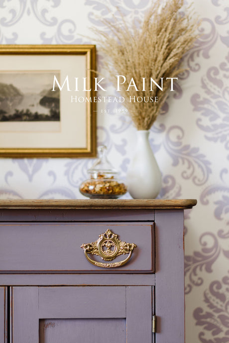 Lavender dresser in Homestead House Lavande Milk Paint with gold handle, glass jar, and white vase on top.
