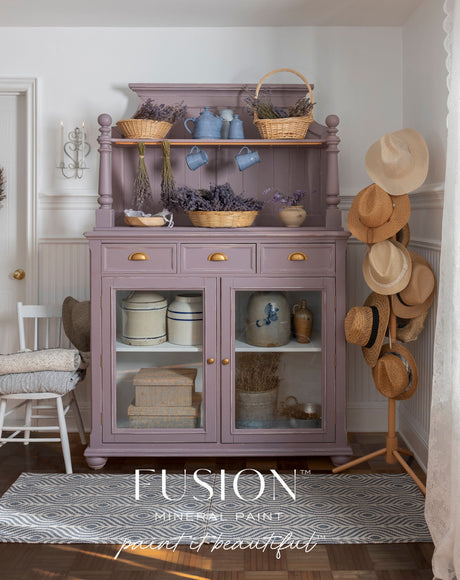 Hutch in Lavender Haze by Fusion Mineral Paint, styled with baskets, books, dried lavender, and hats on a stand.