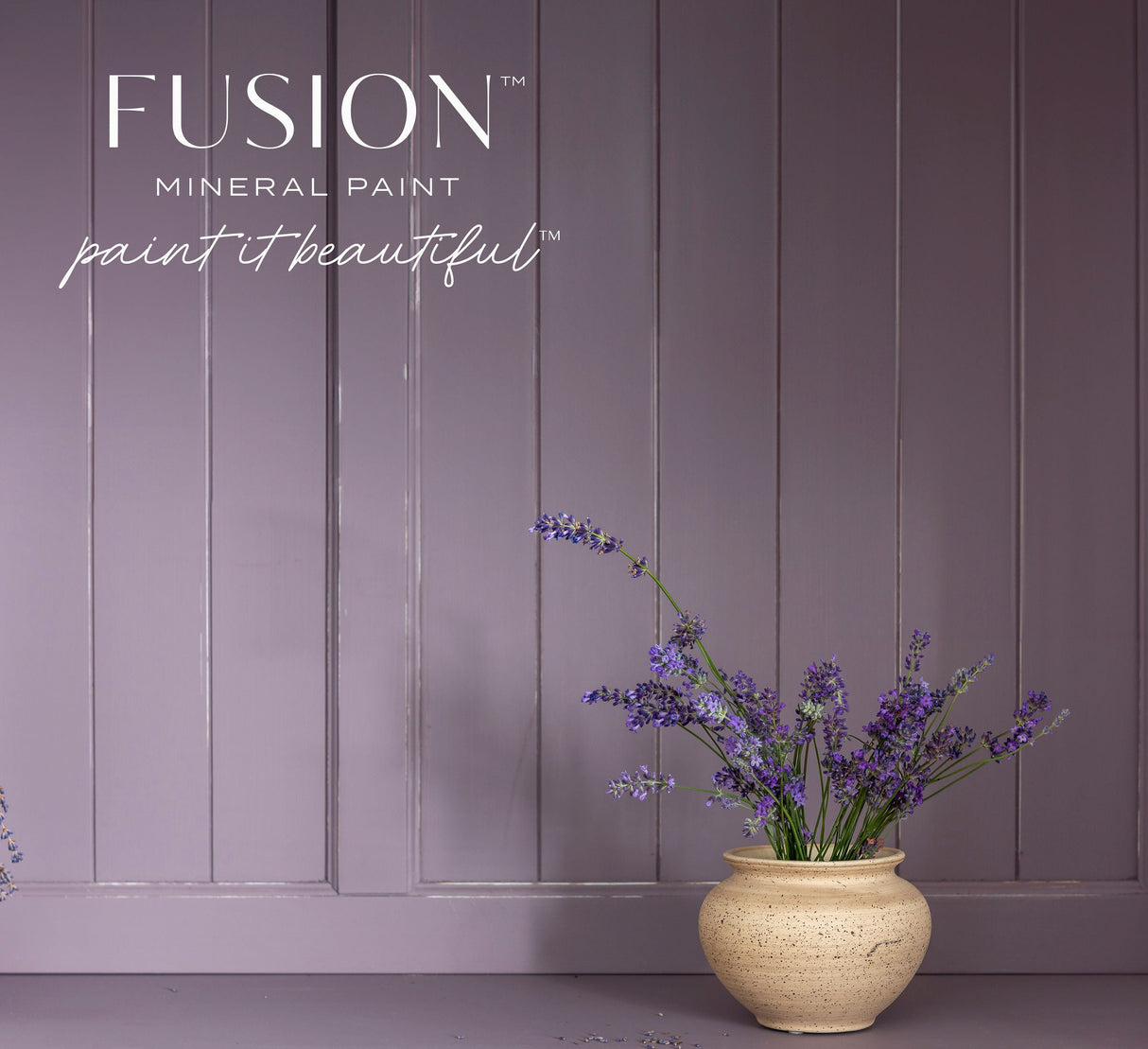Beige vase with purple flowers in front of a mauve wall painted in Fusion Mineral Paint’s Lavender Haze.