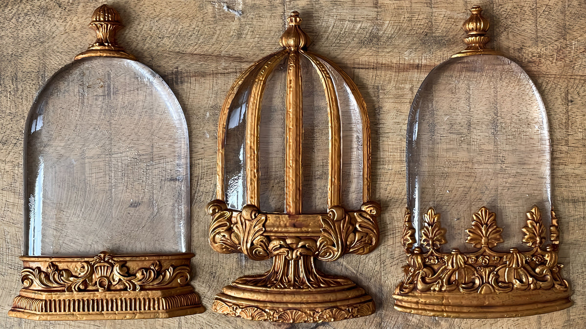 Three gold display cases with glass domes inspired by I.O.D.’s Les Cloches Mould by Iron Orchid Designs.