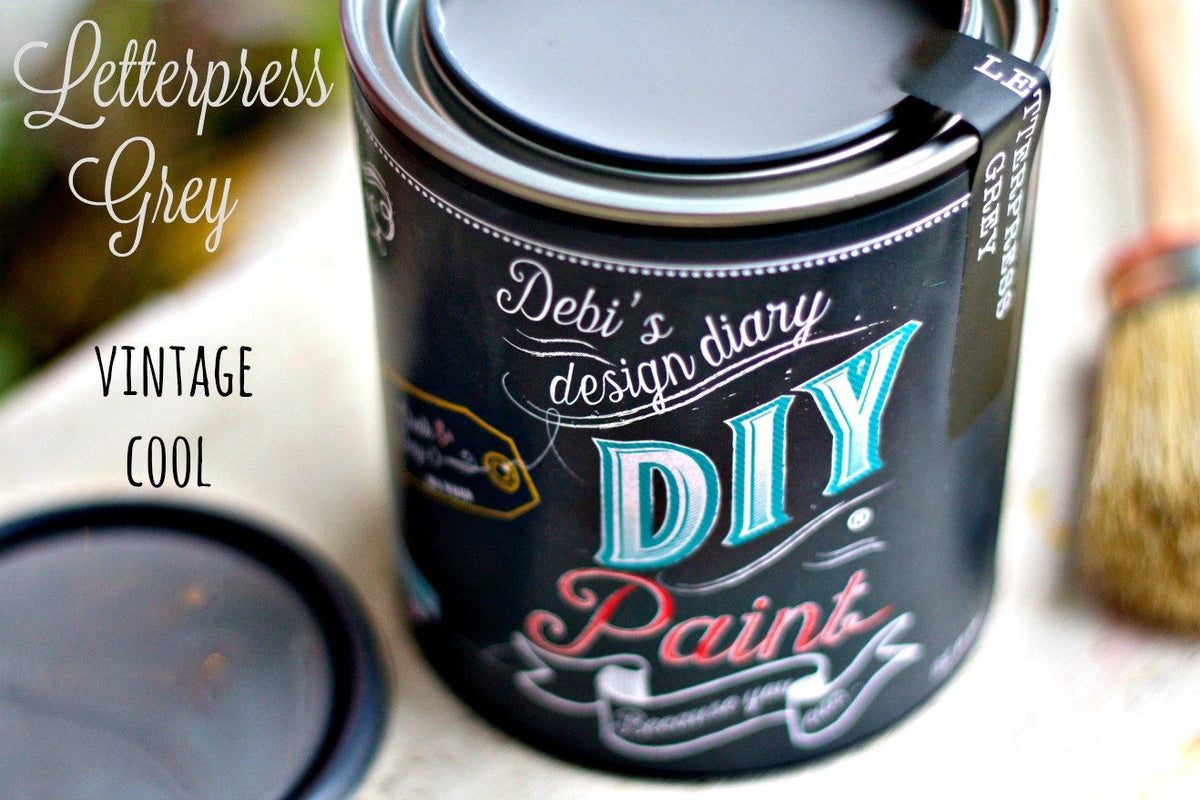 Open can of DIY Paint Co. Letterpress Grey with paintbrush and lid; eco-friendly clay and chalk paint.
