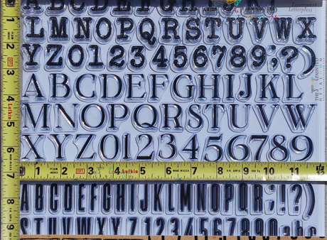 IOD Letterpress Stamp set with metallic letters, numbers, and yellow tapes from I.O.D., shown for DIY stamping projects.