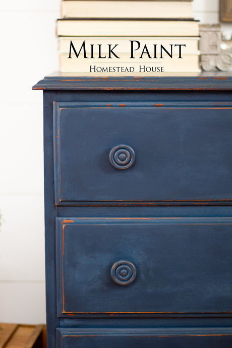 Blue dresser painted in Liberty Blue Milk Paint by Homestead House, shown with books arranged on top.