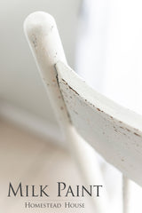 White chair with distressed finish painted in Limestone Milk Paint by Homestead House; branding shown below.