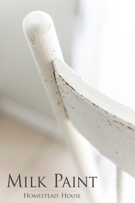White chair with distressed finish painted in Limestone Milk Paint by Homestead House; branding shown below.
