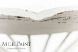 Distressed white chair painted in Limestone Milk Paint by Homestead House, brand text visible in corner.