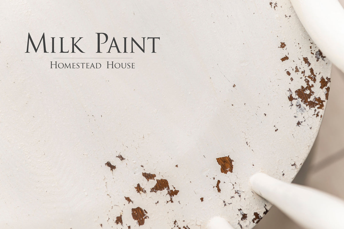 White-painted wood with chips and black “Limestone Milk Paint by Homestead House” text.