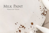 White-painted wood with chips and black “Limestone Milk Paint by Homestead House” text.