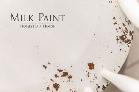 White-painted wood with chips and black “Limestone Milk Paint by Homestead House” text.