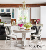 White kitchen scene with round table, flowers, cake; Homestead House Limestone Milk Paint text displayed.
