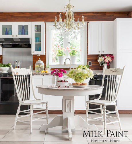 White kitchen scene with round table, flowers, cake; Homestead House Limestone Milk Paint text displayed.