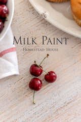Three red cherries beside a plate and cloth, with text: Limestone Milk Paint by Homestead House.