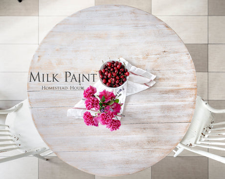 Round table painted with Limestone Milk Paint by Homestead House, pink flowers, cherries, two white chairs.