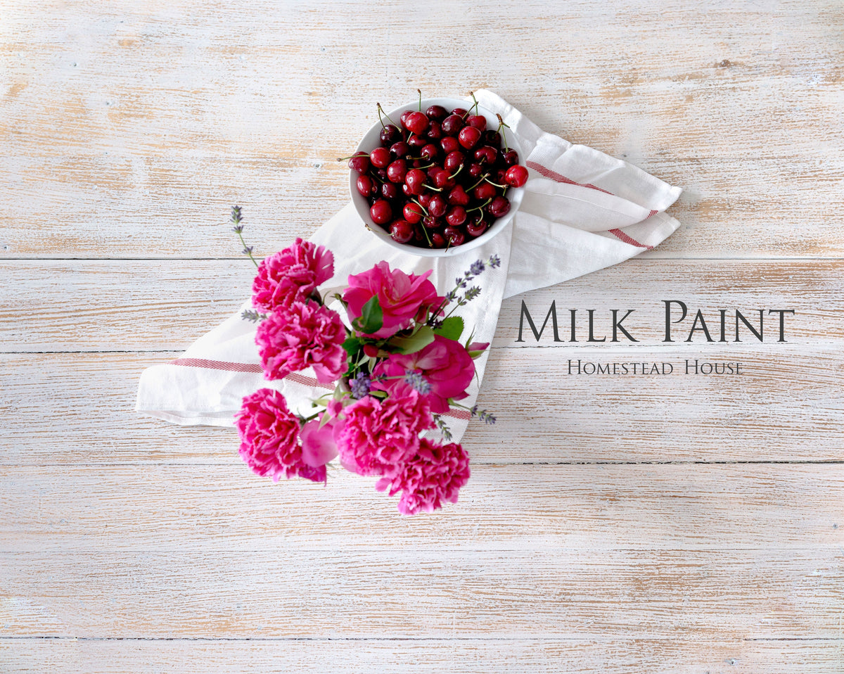 Limestone Milk Paint by Homestead House text on wood, with cherries and pink flowers on white cloth.