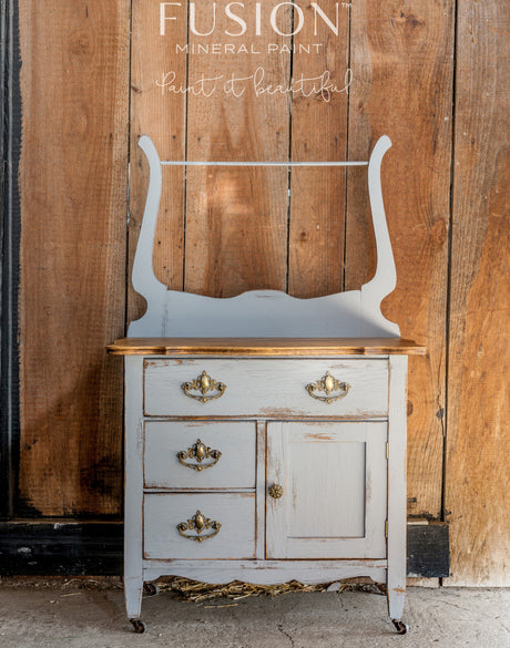 Small gray wooden cabinet painted in Little Lamb Fusion Mineral Paint with brass pulls.