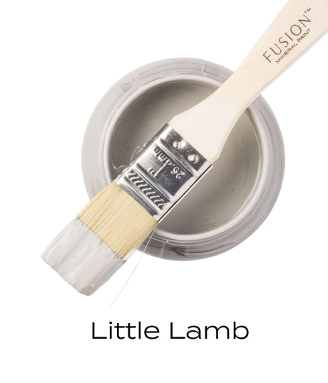 Brush with gray Little Lamb Fusion Mineral Paint resting on open jar labeled Little Lamb Fusion Mineral Paint.