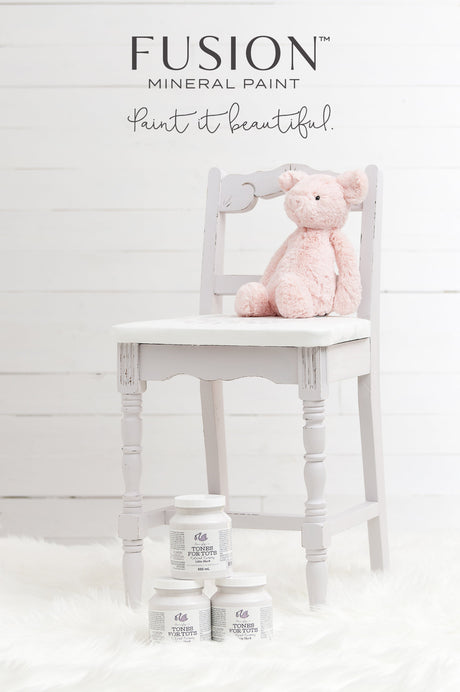 Light gray chair with a pink plush pig and three Little Stork Fusion Mineral Paint jars on a white fur rug.