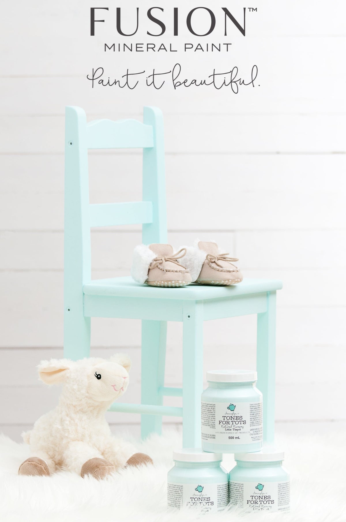 Light blue chair with baby shoes, a stuffed lamb, and Fusion Mineral Paint Little Teapot jars on white furry rug.