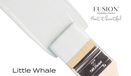 Paintbrush with blue paint next to a container labeled “Little Whale Fusion Mineral Paint” by Fusion Mineral Paint.