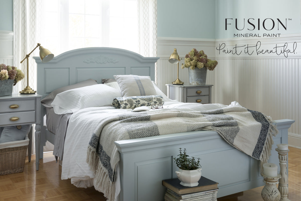 Light blue bed painted in Little Whale Fusion Mineral Paint with white linens and plaid throw, shown with twin side tables.