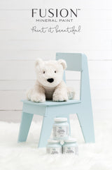 White stuffed bear on chair with Little Whale Fusion Mineral Paint jars on a white furry rug below.
