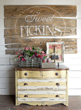 Yellow dresser painted in Old Fashioned Milk Paint Love Bug, shown beneath a rustic Sweet Pickins wood sign.