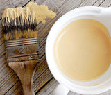 Brush with Love Bug by Old Fashioned Milk Paint next to a cup of matching beige paint on wood surface.