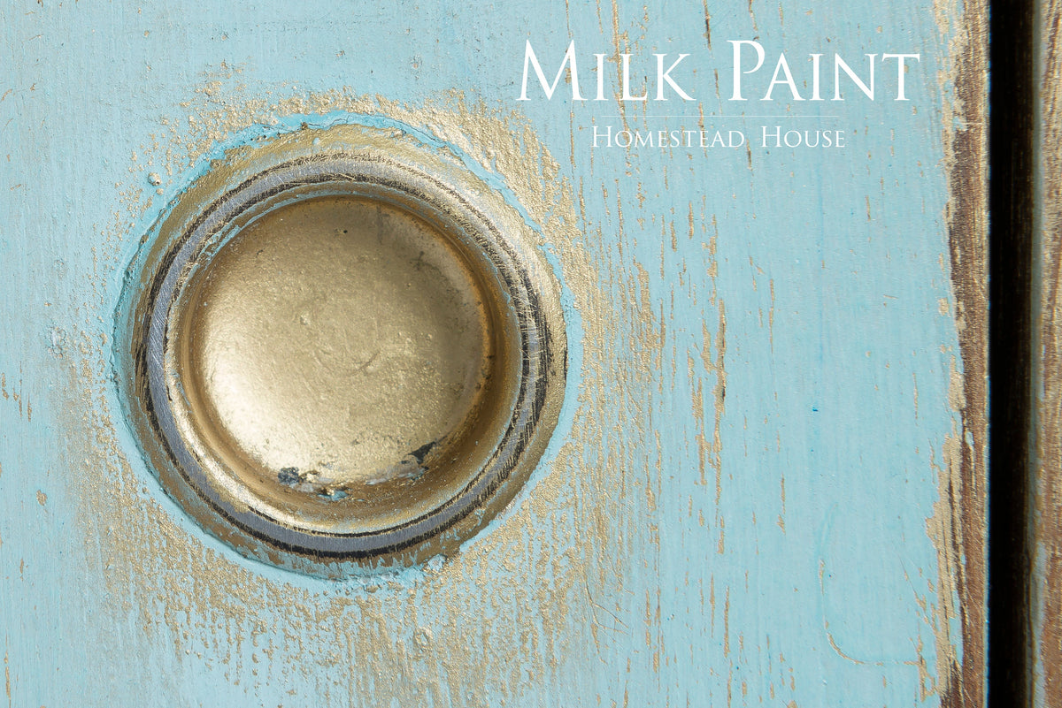 Round brass handle on distressed blue wood, Homestead House Loyalist Milk Paint text in corner.