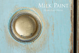 Round brass handle on distressed blue wood, Homestead House Loyalist Milk Paint text in corner.