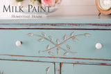 Distressed turquoise dresser with white knobs, leaf carvings, and Loyalist Milk Paint by Homestead House.