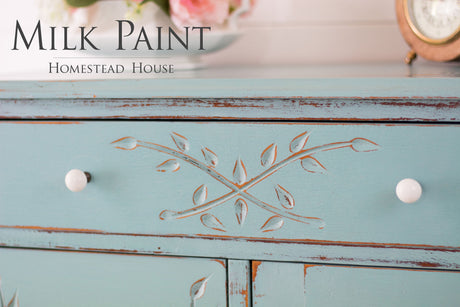 Distressed turquoise dresser with white knobs, leaf carvings, and Loyalist Milk Paint by Homestead House.