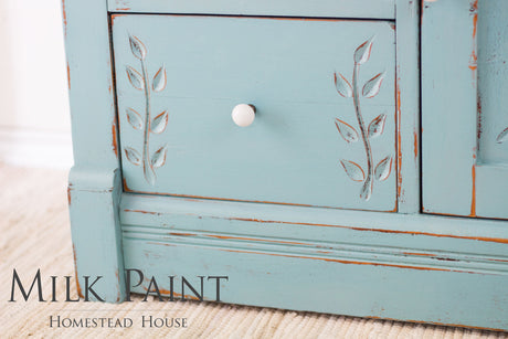 Blue Loyalist Milk Paint drawer with leaf carvings, white knob, and Homestead House branding visible.