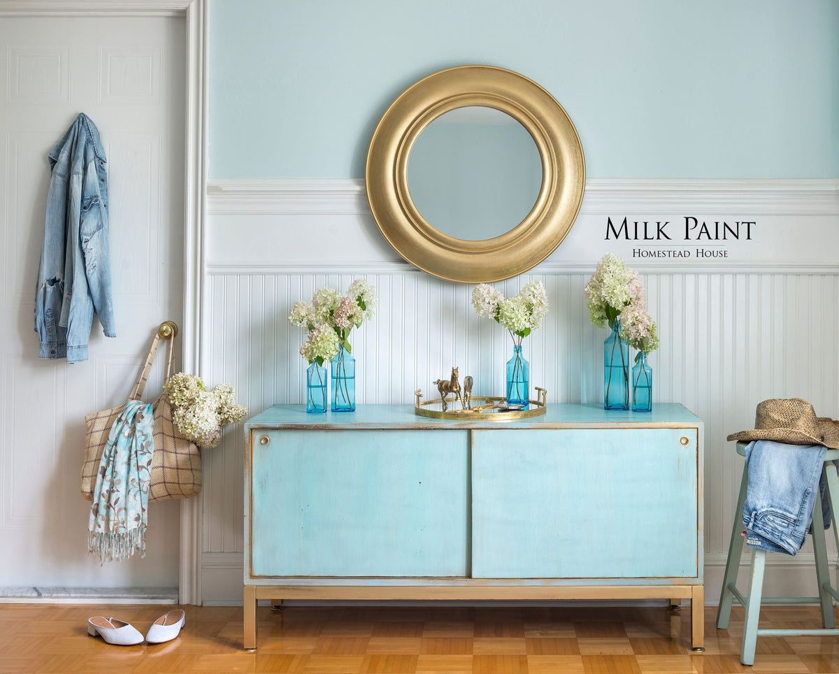 Loyalist Milk Paint sideboard by Homestead House, decorated with flowers, gold mirror, and denim jacket.