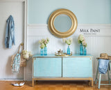 Loyalist Milk Paint sideboard by Homestead House, decorated with flowers, gold mirror, and denim jacket.