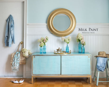 Loyalist Milk Paint sideboard by Homestead House, decorated with flowers, gold mirror, and denim jacket.