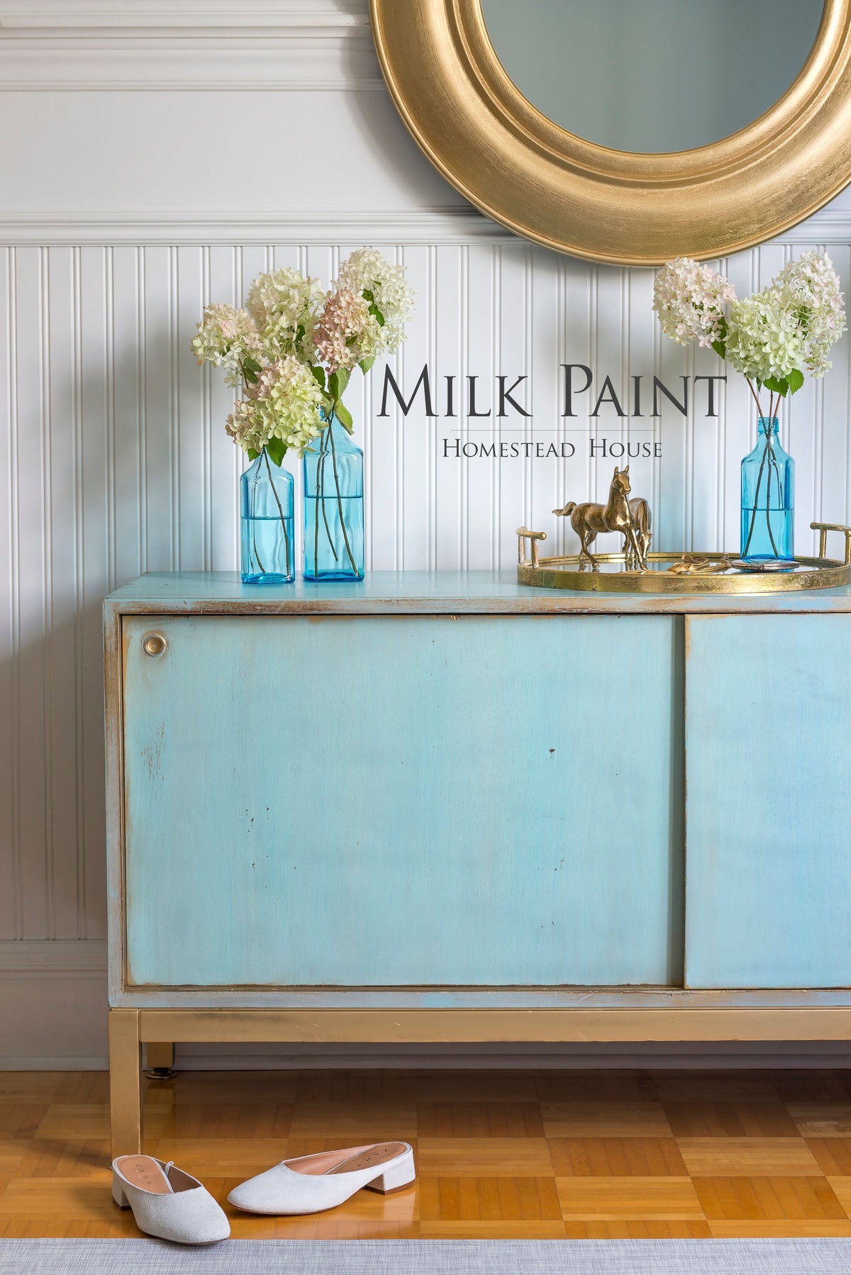 Blue sideboard painted with Homestead House Loyalist Milk Paint, gold trim, vases, mirror, tray, and white shoes.