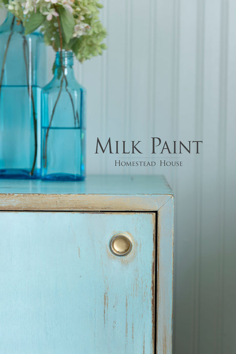 Light blue cabinet in Loyalist Milk Paint by Homestead House with brass knob; text reads “Milk Paint.”.