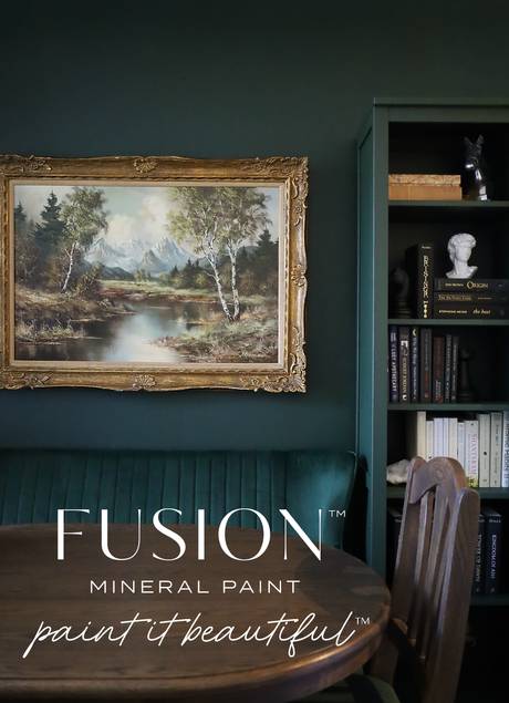 Framed landscape above green sofa in Manor Green by Fusion Mineral Paint, round table, and bookshelf.