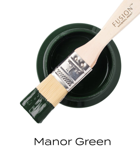 Open jar of Manor Green Fusion Mineral Paint with brush resting on top; text below reads “Manor Green.”.