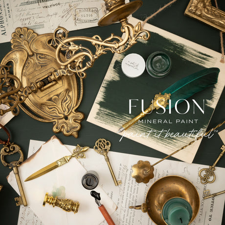 Antique keys, feather quill, Fusion’s Manor Green paint pots, and vintage documents arranged on a flat surface.