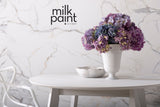 White round table with a vase, bowl, and Fusion Mineral Paint Marble Milk Paint packaging visible.
