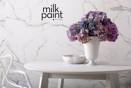 White round table with a vase, bowl, and Fusion Mineral Paint Marble Milk Paint packaging visible.
