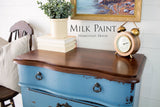 Blue distressed dresser in Homestead House Maritime Blue Milk Paint with wood top; books and a plant on top.