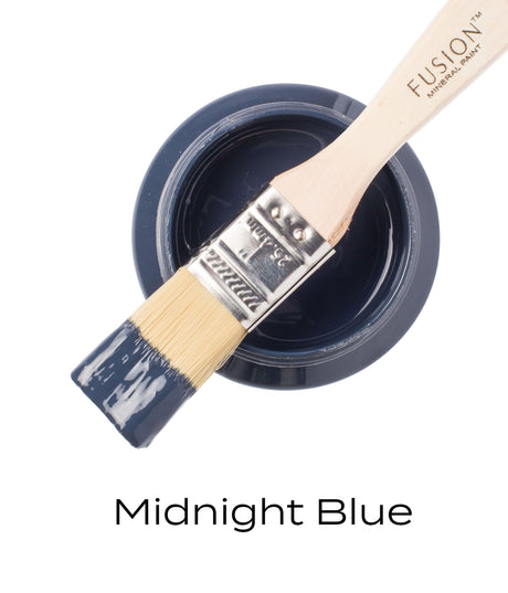 Brush resting on open can of Midnight Blue Fusion Mineral Paint, bristles dipped in deep blue paint.
