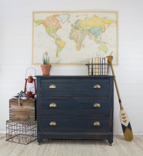 Homestead House Midnight Blue Milk Paint dresser beneath a map, with shoes and oars placed at its side.