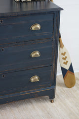 Navy dresser in Homestead House Midnight Blue Milk Paint with brass handles on a beige rug.