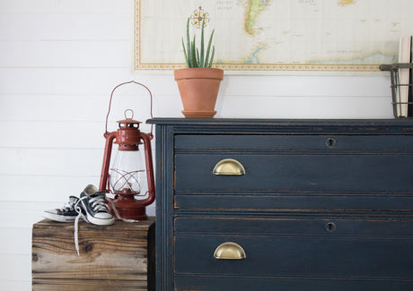 Midnight Blue Milk Paint dresser by Homestead House with brass handles, a succulent, red lantern, and sneakers on top.